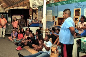 a large group of visitors sitting on the floor and standing around during a group program