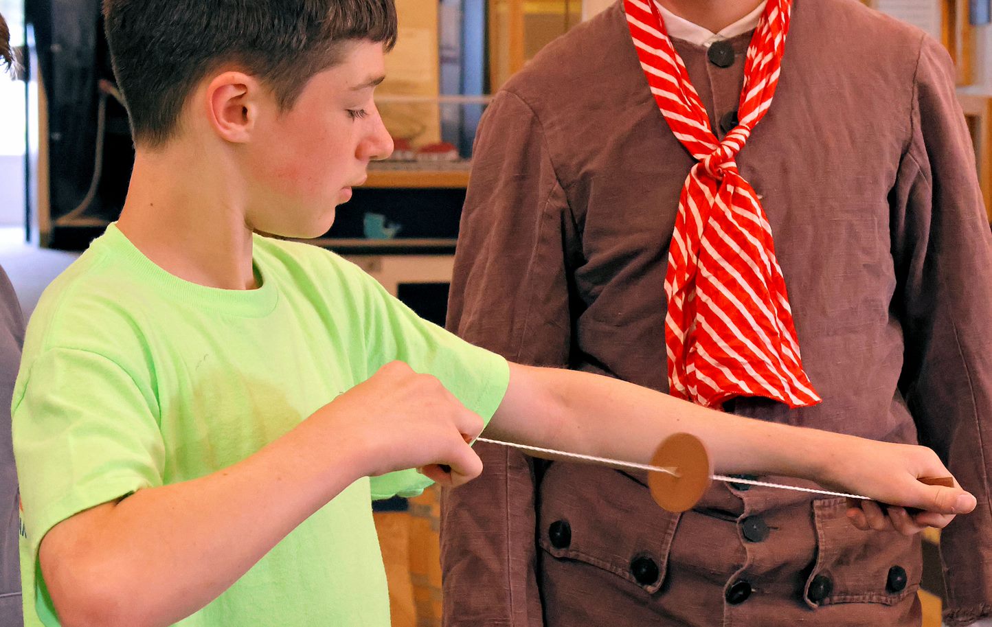 Boy holds a hand-crafted spinning toy composed of string with a disc on it