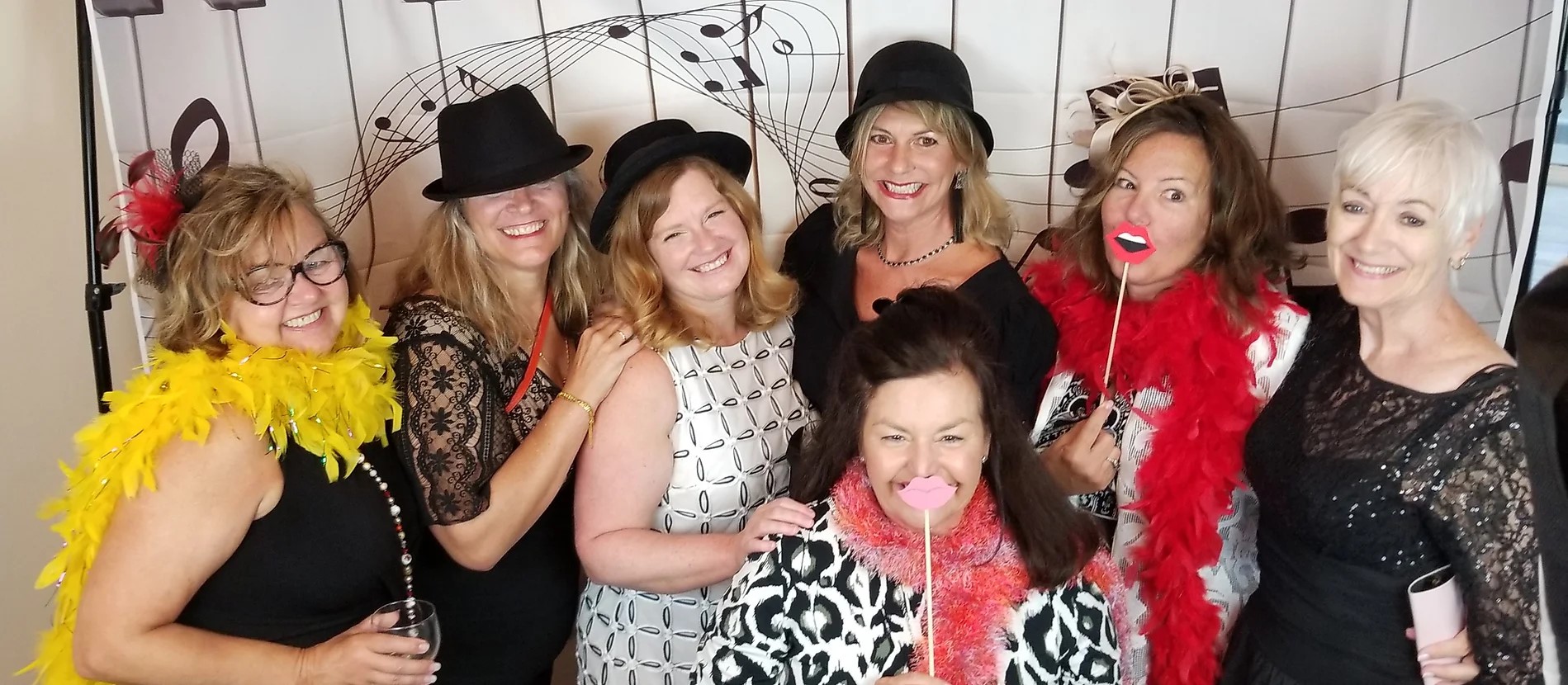 seven white mature women posing with hats and other props in front of a backdrop with musical symbols on it